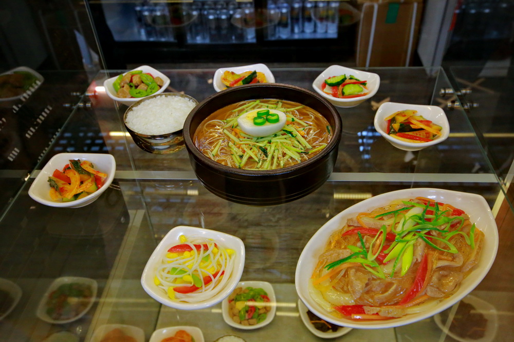 Можно пожарить мясо верхом на грибах, чтобы не пригорело. Разрезать готовое блюдо ножницами. Кусочки мяса, перед тем как есть, обмакнуть в масло кунжута. Закуски завернуть в лист салата, как голубец. И всё это — вприкуску с супом.