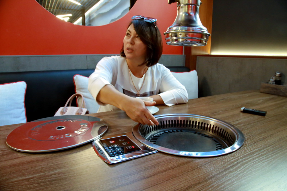 На столах установлены барбекю, где можно самому пожарить мясо. К нему подают чугунок с супом, рис и пять видов корейских закусок.