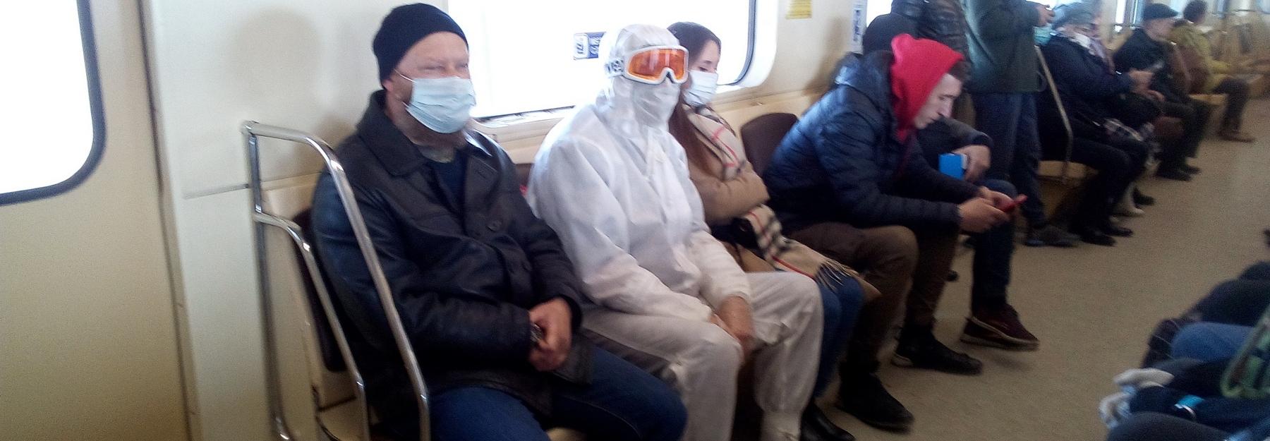 Напуганный коронавирусом человек в защитном костюме разъезжает в метро